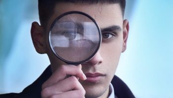 man in black suit holding magnifying glass
