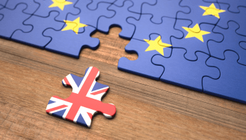 A photo of a jigsaw of the blue EU flag with one piece missing. the missing piece just to one side is a Union Jack flag